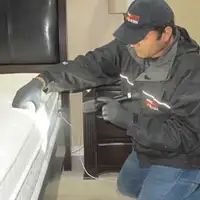 Bed bug inspection technician checking a mattress and bed frame for signs of infestation in Long Beach, CA