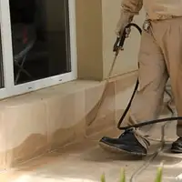 General pest control technician spraying exterior perimeter around a home in Long Beach, CA