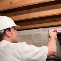 Termite inspection technician checking a basement wall and framing for termite activity in Long Beach, CA
